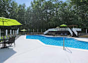 Thumbnail 4 of 15 - A pool with a white fence and trees in the background.