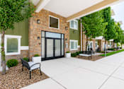 Thumbnail 6 of 20 - Apartment building entrance with stone accents and landscaping at The Ellison Apartments, Layton, UT