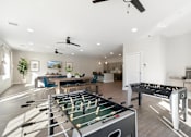 Thumbnail 26 of 36 - A foosball table is in the middle of a room with a ping pong table in the foreground.
