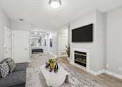Thumbnail 2 of 26 - A modern living room with a grey couch and a fireplace.
