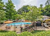 Thumbnail 12 of 26 - A pool surrounded by a black fence and trees.