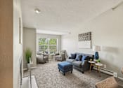 Thumbnail 1 of 24 - A living room with a grey couch and a blue ottoman.