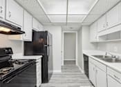 Thumbnail 8 of 28 - A kitchen with black appliances and white cabinets.