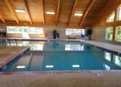 Thumbnail 51 of 58 - a swimming pool in a building with a wooden ceiling and a large window