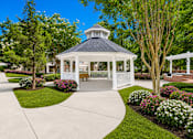 Thumbnail 3 of 15 - A gazebo is surrounded by a white picket fence and a variety of flowers.