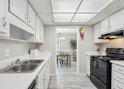 Thumbnail 9 of 28 - A kitchen with white cabinets and a black stove top oven.
