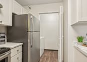 Thumbnail 10 of 24 - A kitchen with a black refrigerator and white cabinets.