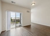 Thumbnail 10 of 56 - A bright living room with wood-style flooring, a sliding glass door leading to an outdoor space, and natural light coming in from outside.