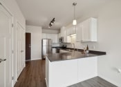 Thumbnail 2 of 56 - A spacious kitchen with modern white cabinetry, a large countertop, stainless steel appliances, and pendant lighting.