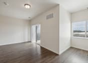 Thumbnail 18 of 56 - A spacious room with wood-style flooring, a sliding glass door leading to an outdoor area, and a ceiling light fixture. The walls are painted neutral tones.