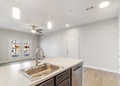 Thumbnail 25 of 36 - A kitchen with a sink, a refrigerator, and a ceiling fan.