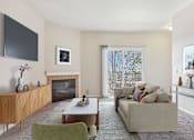 Thumbnail 1 of 36 - A living room with a fireplace, a couch, a chair, and a TV mounted on the wall.