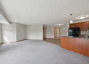 Thumbnail 26 of 58 - a spacious living room with a kitchen and a carpeted floor
