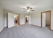 Thumbnail 29 of 58 - an empty living room with a ceiling fan and doors to a bedroom and a bathroom