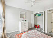 Thumbnail 15 of 28 - A bedroom with a dresser, mirror, and a ceiling fan.