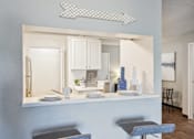 Thumbnail 5 of 24 - A kitchen with a white counter and a grey stool.