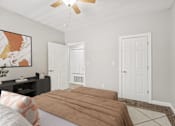 Thumbnail 9 of 26 - A bedroom with a bed, a ceiling fan, and a painting on the wall.