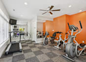 Thumbnail 15 of 26 - A home gym with a treadmill, elliptical machines, and a television.