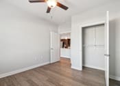 Thumbnail 8 of 36 - A room with a ceiling fan and wooden flooring.