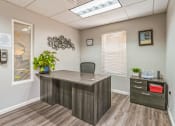 Thumbnail 14 of 39 - A grey reception desk with a plant on it and a framed picture on the wall.