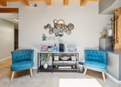 Thumbnail 33 of 39 - a living room with two blue chairs and a table and a wall with a shelf