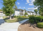 Thumbnail 11 of 20 - an apartment building with a sidewalk and grass and trees