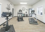 Thumbnail 9 of 18 - A gym with a treadmill, elliptical machines, and a clock on the wall.