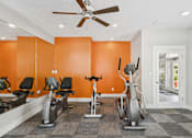 Thumbnail 16 of 26 - A gym with orange walls and a variety of exercise equipment.