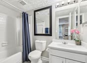 Thumbnail 16 of 28 - A white bathroom with a toilet, sink, and mirror.