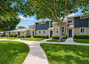 Thumbnail 2 of 9 - A tree stands in front of a building with a walkway in front of it.