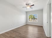 Thumbnail 7 of 36 - A room with a ceiling fan and a window showing trees outside.