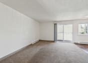 Thumbnail 9 of 32 - an empty living room with a sliding glass door to a balcony
