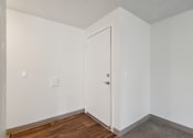 Thumbnail 14 of 32 - a bedroom with white walls and wood flooring and a white door