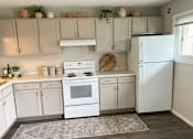 Thumbnail 13 of 14 - A white kitchen with a white fridge and white cabinets.