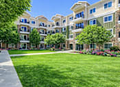 Thumbnail 1 of 26 - Central courtyard with lawn and flower beds at The Beckstead Apartments, South Jordan, Utah