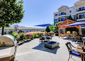 Thumbnail 15 of 26 - Outdoor patio with fire pit and pergola seating at The Beckstead Apartments, South Jordan, UT