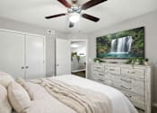 Thumbnail 20 of 23 - A bedroom with a large bed, a ceiling fan, and a waterfall mural on the wall.