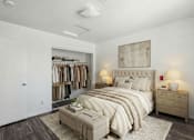 Thumbnail 11 of 11 - A bedroom with a large bed, a clothing rack, and a nightstand with lamps.