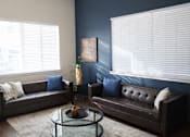 Thumbnail 8 of 13 - A living room with a brown couch and a coffee table.
