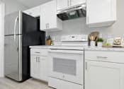 Thumbnail 11 of 17 - A modern kitchen with white appliances and cabinets.