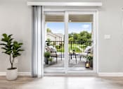 Thumbnail 16 of 17 - A patio with a table and chairs is visible through a sliding glass door.