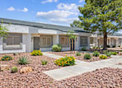 Thumbnail 4 of 11 - A white building with a grey roof and a tree in front.