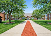Thumbnail 2 of 14 - A red brick pathway leads to a building entrance.