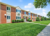 Thumbnail 3 of 14 - A row of red brick apartment buildings with green lawns in front.