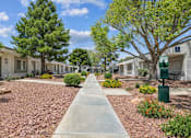 Thumbnail 3 of 11 - A concrete pathway leads through a row of houses with trees on either side.
