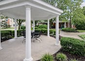 Thumbnail 1 of 20 - A white covered patio with a table and chairs.