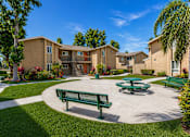 Thumbnail 5 of 21 - A sunny day at a residential complex with a green bench and picnic table.