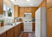 Thumbnail 16 of 21 - A kitchen with wooden cabinets and a white refrigerator.