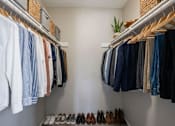 Thumbnail 20 of 21 - A closet with clothes and shoes neatly arranged.