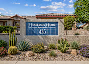 Thumbnail 1 of 13 - A sign for Henderson Manor Apartments is displayed in front of a building.